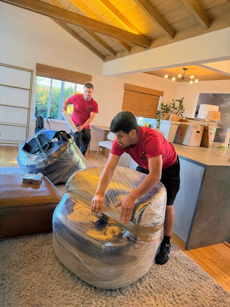 Long distance San Francisco movers packing and wrapping furniture in a home.