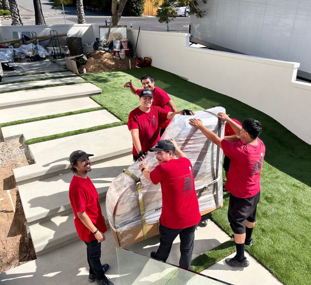 NorthStar Moving team moving a carefully wrapped piano