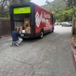 A photographer by a NorthStar Moving electric van during a move for the 49ers Foundation's 2026 annual Golden Getaway Weekend & Celebrity Golf Tournament