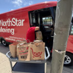 Donation bags collected by the Jones & Jones community as part of Move for Hunger's Multifamily program. A NorthStar Moving team member is loading them into our electric van, used to deliver them to the Hollywood Food Coalition.
