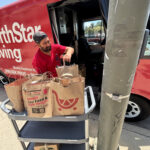 Donation bags collected by the Jones & Jones community as part of Move for Hunger's Multifamily program. A NorthStar Moving team member is loading them into our electric van, used to deliver them to the Hollywood Food Coalition.
