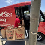 Donation bags collected by the Jones & Jones community as part of Move for Hunger's Multifamily program. A NorthStar Moving team member is loading them into our electric van, used to deliver them to the Hollywood Food Coalition.